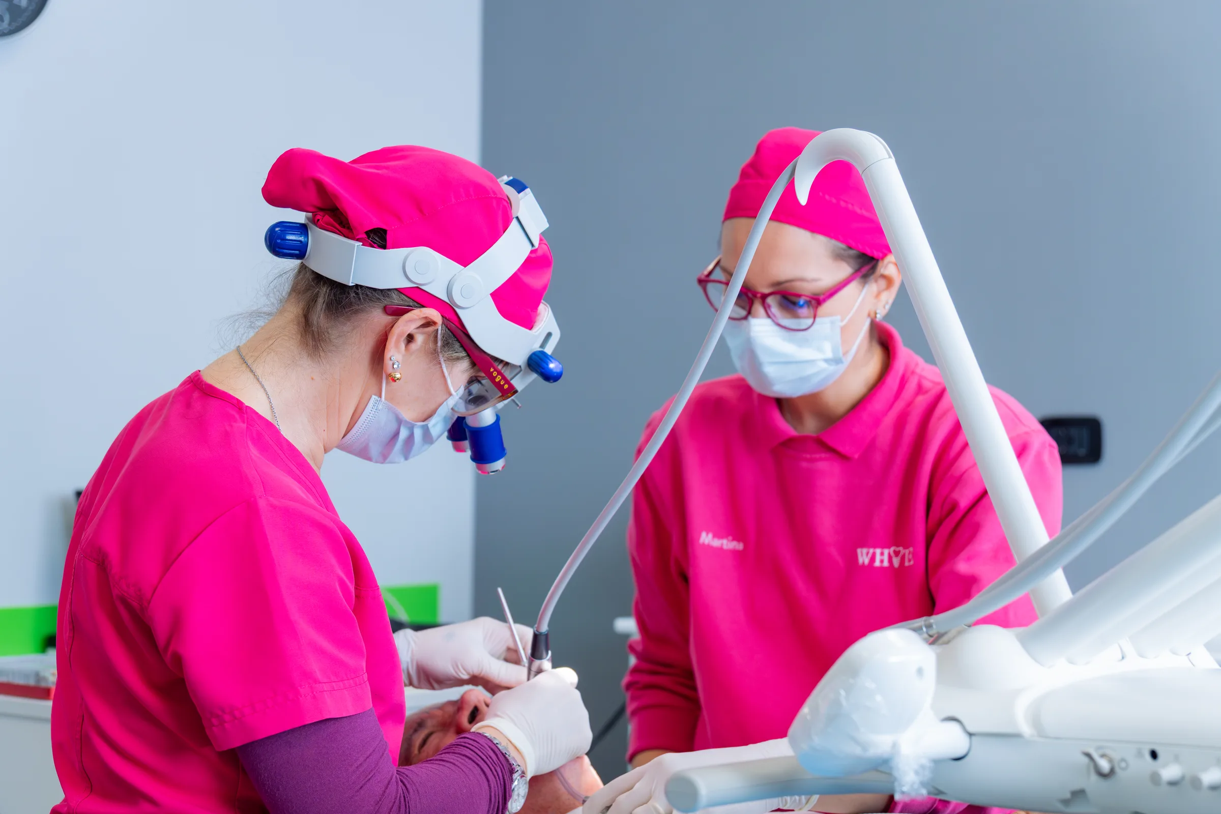 Due professioniste dello studio dentistico White, in divisa rosa, al lavoro sul riunito